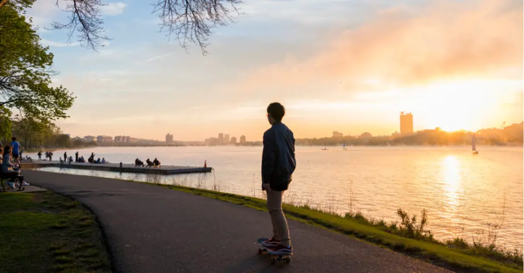 A boy skateboards along the Charles River Esplanade in Boston, Massachusetts, at sunset.