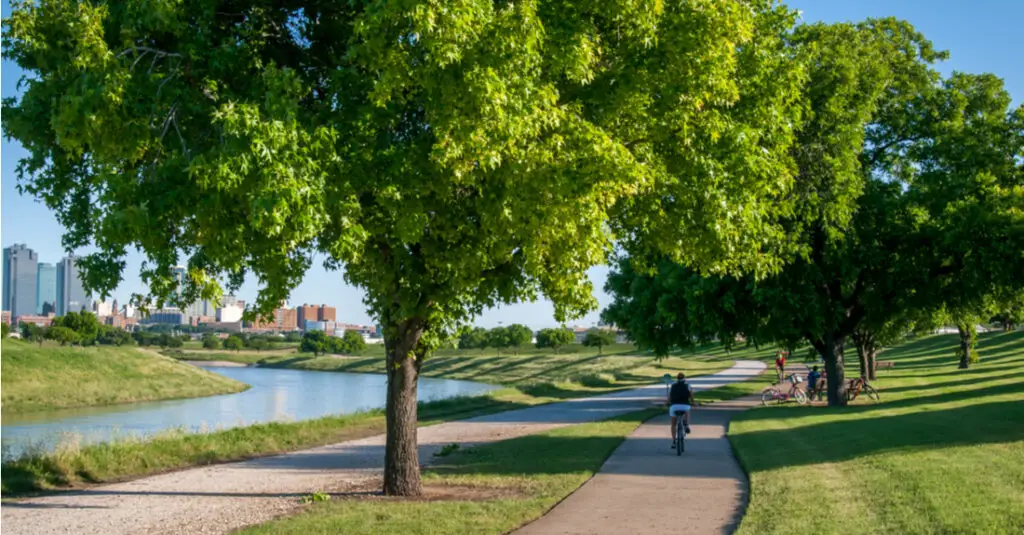 A cyclist rides along the Trinity Trails next to the Trinity River with the Fort Worth, Texas, skyline in the background.