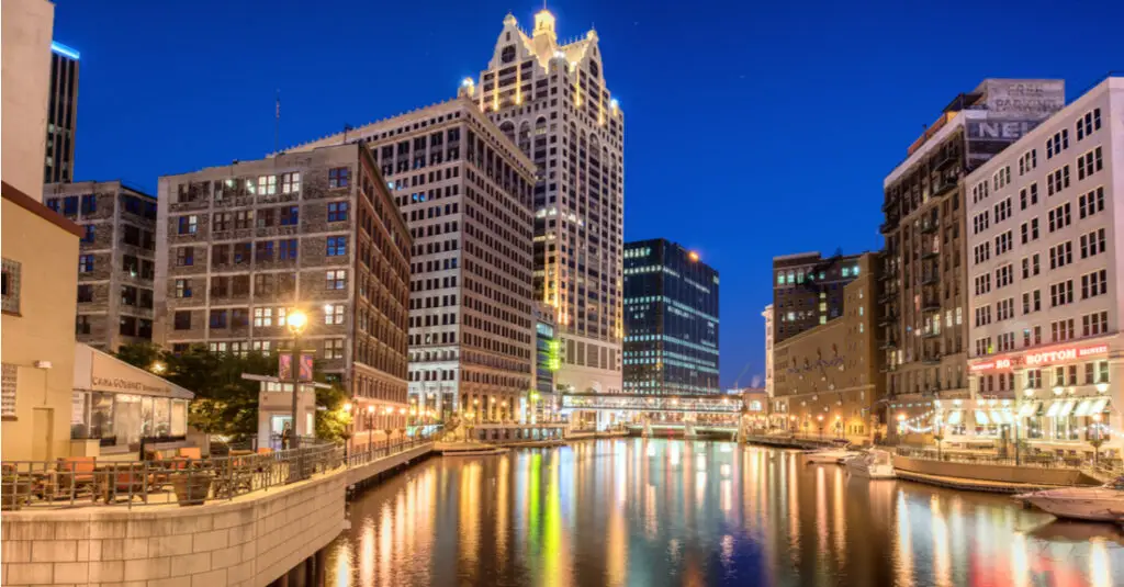 The Milwaukee RiverWalk and the downtown Milwaukee skyline at night, with city lights reflecting on the water.