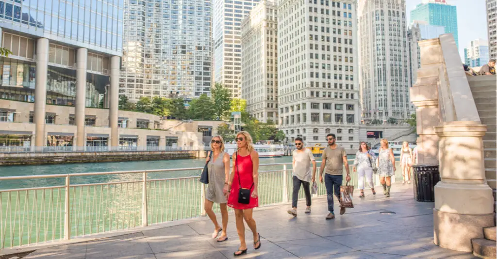 A group of people walking along the Chicago Riverwalk in the summertime.