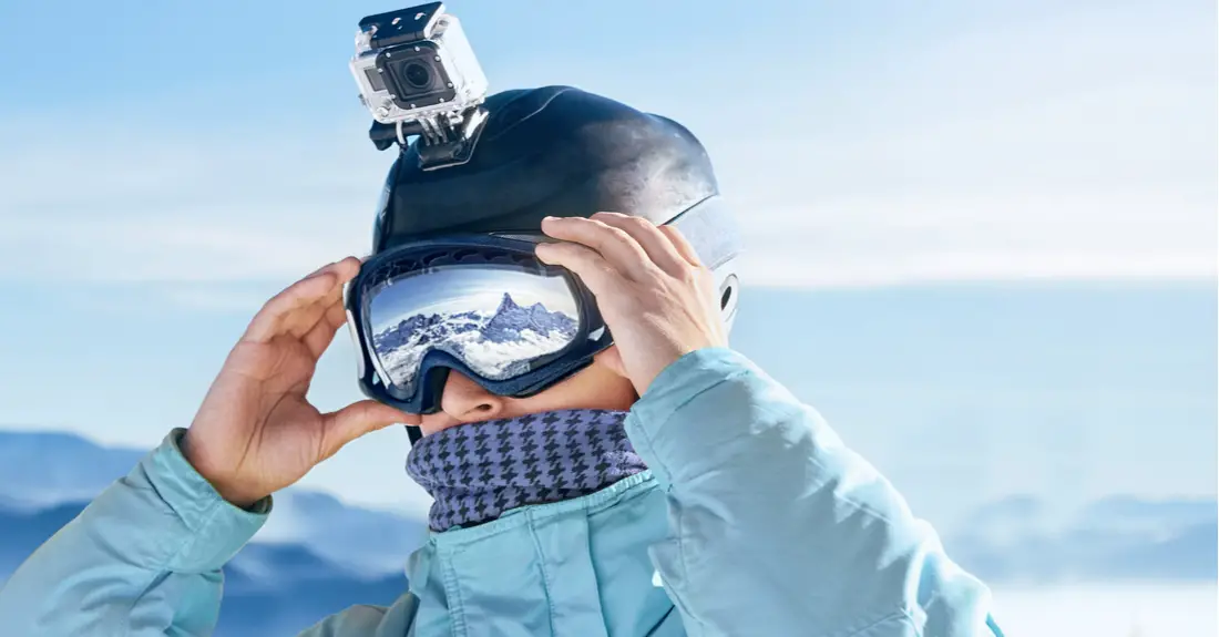 A skier mounts a GoPro camera on their helmet.