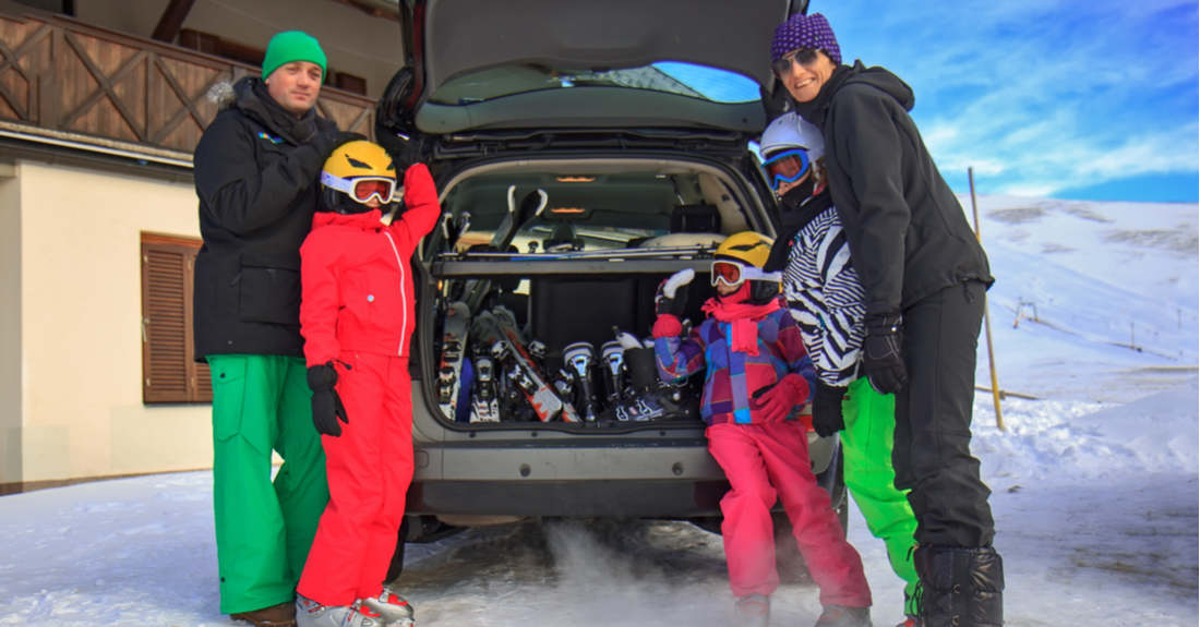 A family of five packs the car with ski gear for a family ski trip.